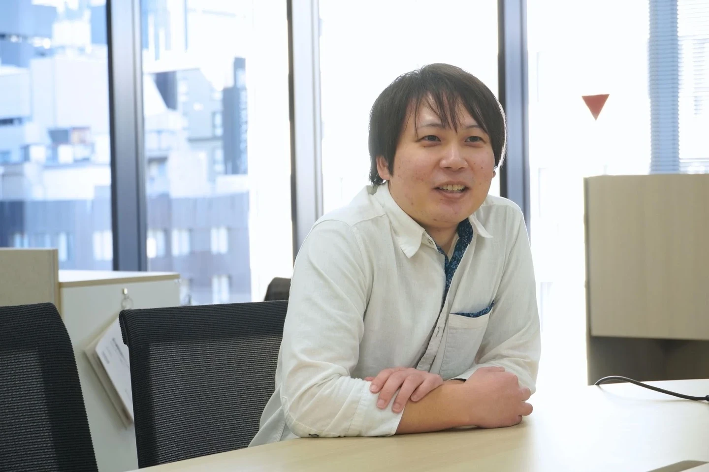 デスクで話す若手男性社員（玉利さん）